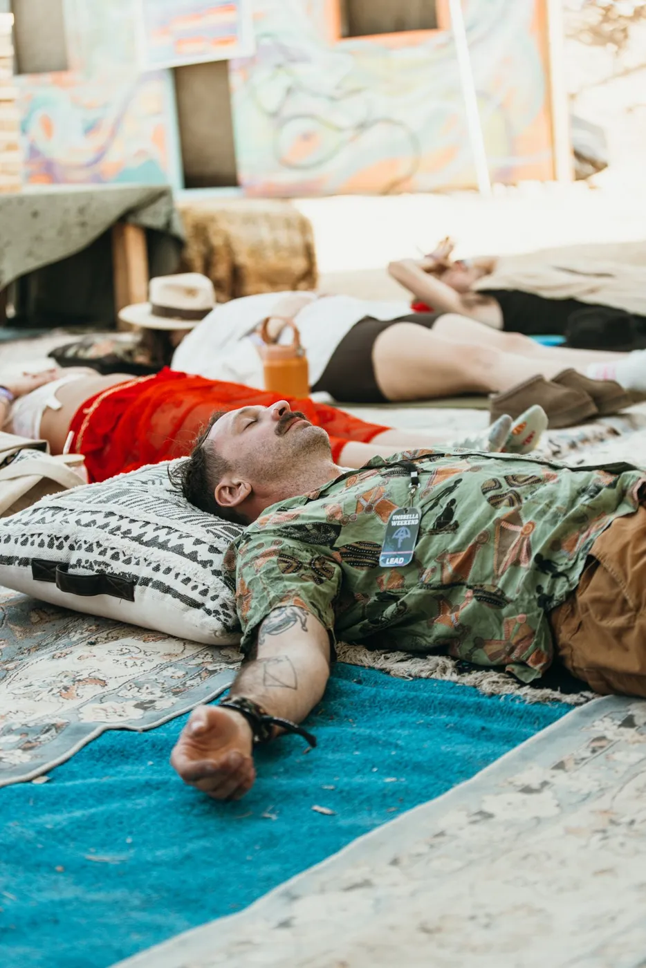 People lying on mats in the shade during a breathwork session at the Oasis
