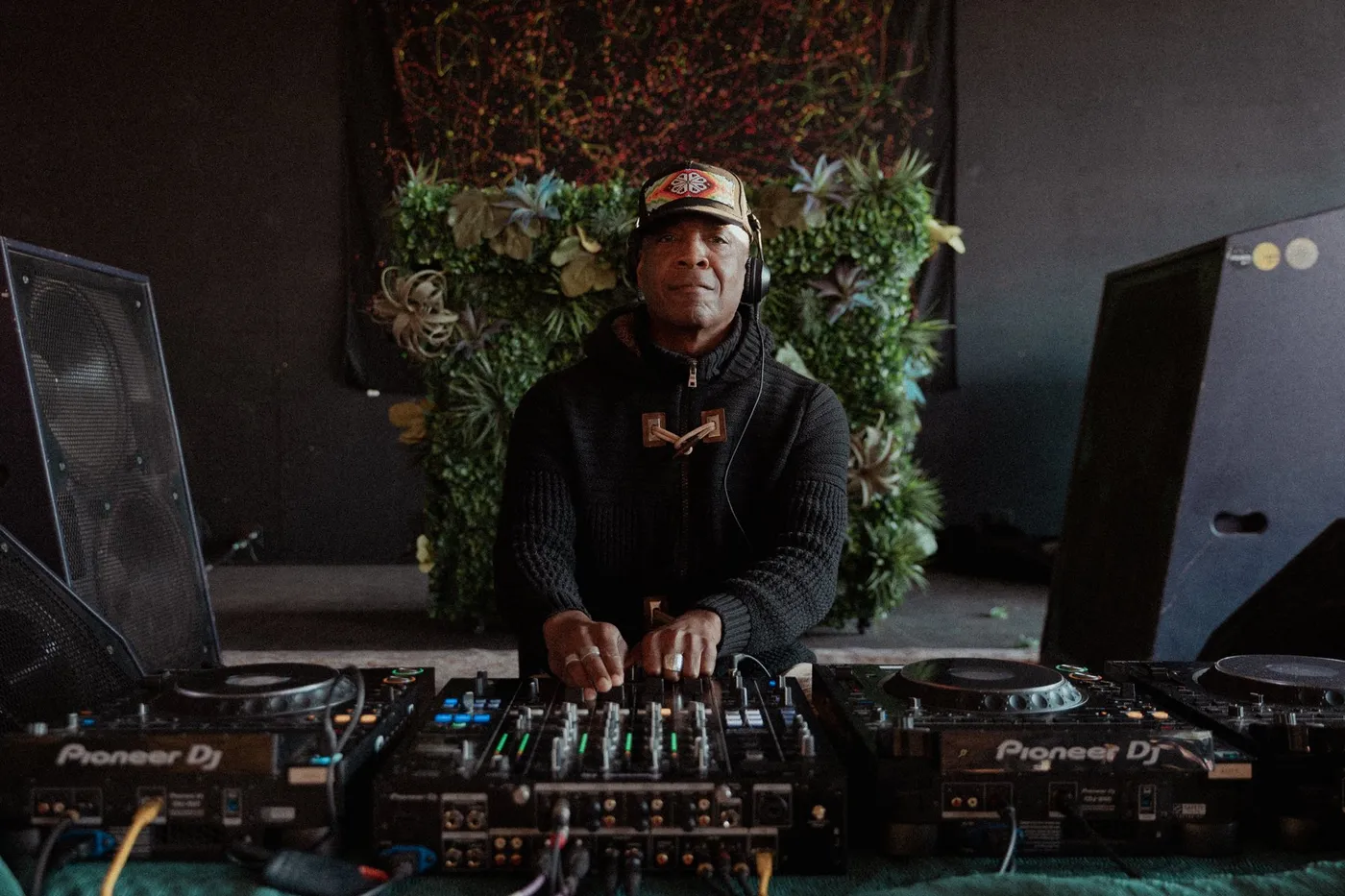 A DJ playing in front of a living plant wall at Press Pause
