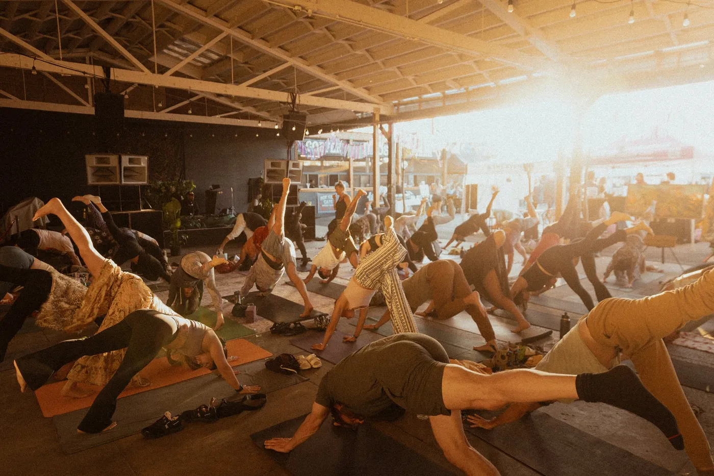 A full room in downward dog at golden hour during Press Pause at the Soap Factory